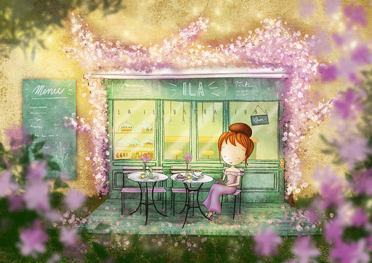Ila Café Postcard by Ila Illustrations featuring a whimsical illustrated scene of a small cafe storefront framed by pink blossoms, with a seated girl at an outdoor table in front. The artwork has a soft, dreamy style with warm yellow light and purple floral foreground blur.