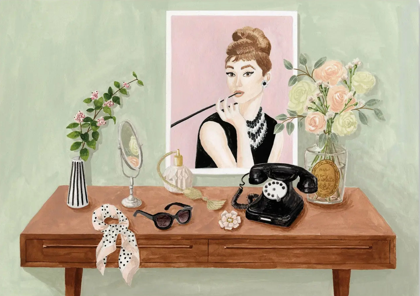 Audrey Hepburn Postcard featuring a desk with a poster of Audrey, flowers, a phone, and other items on a light green background. Postcard by MELANIE VOITURIEZ.