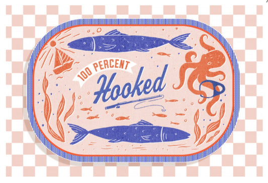 Dockside Series - 100% Hooked Postcard by Lantern Press featuring blue fish, an orange octopus, and the words “100 Percent Hooked” on a pale pink background