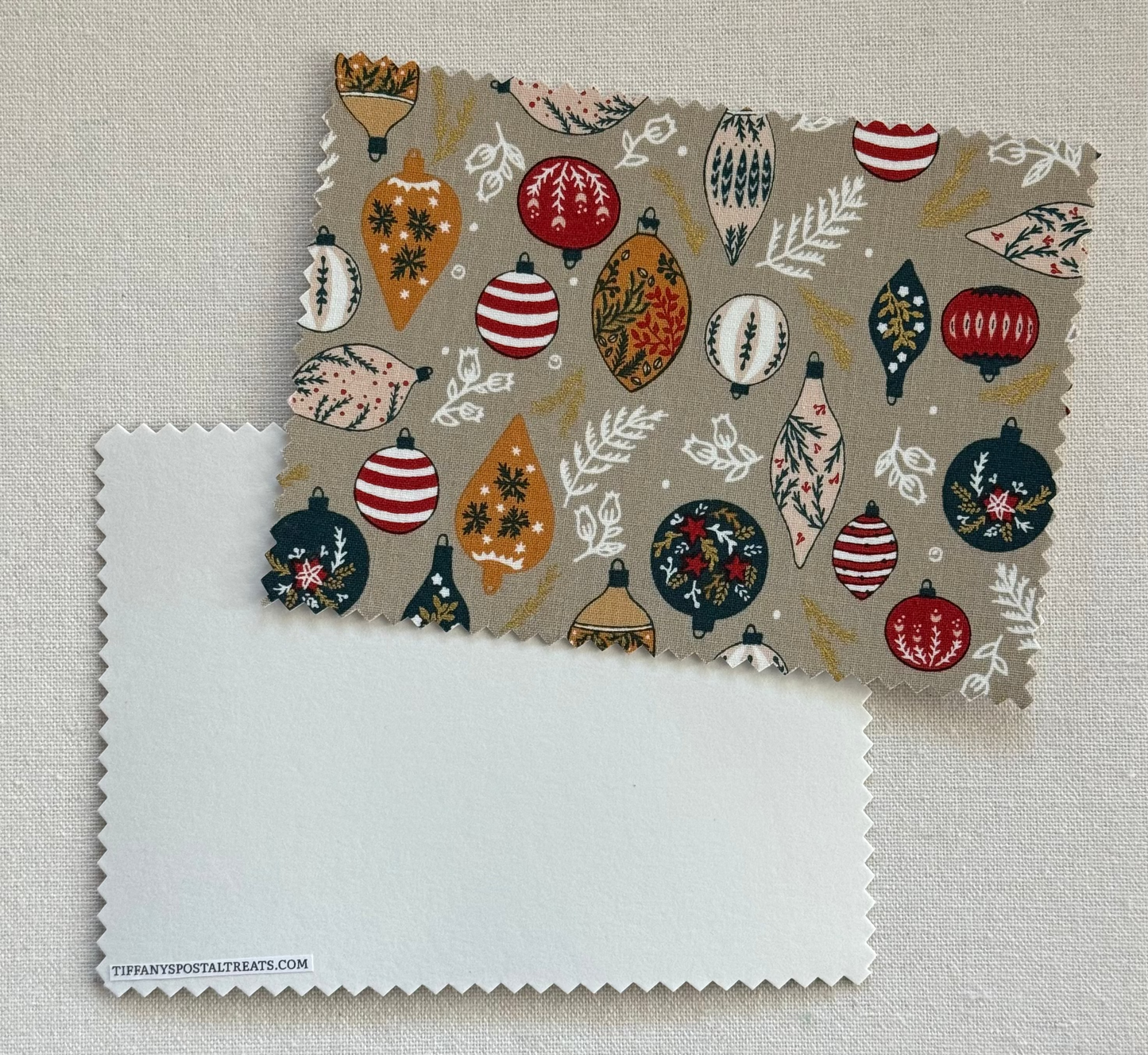 Fabric Postcard with Christmas ornaments on a beige background.