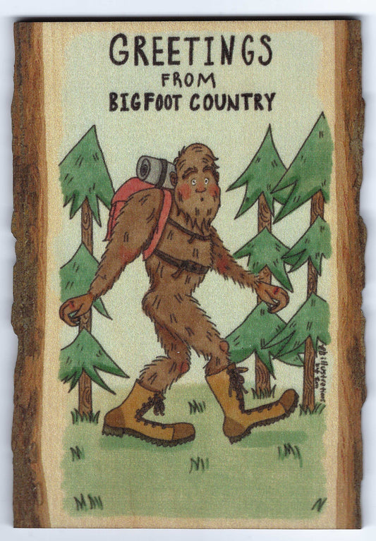 Greetings from Bigfoot Country postcard with Sasquatch in a forest setting.