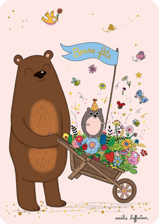 Happy Day Bear Postcard by Cartes d'Art showing a large brown bear pushing a wheelbarrow filled with flowers, a small hedgehog wearing a party hat, butterflies, bees, stars, and confetti, with a blue banner reading “Bonne Fête.”.