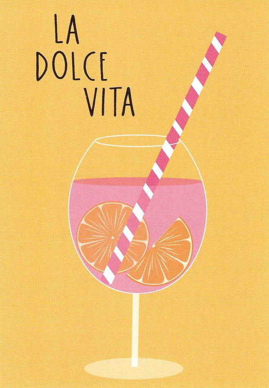 La Dolce Vita Cocktail Postcard by Nobis Design featuring a pink drink in a wine glass with orange slices and a pink-and-white striped straw on a warm yellow background, with the text 'LA DOLCE VITA' in gold foil at the top.