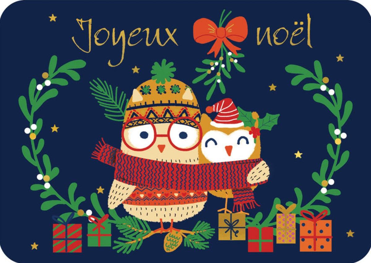 Merry Christmas Owls Postcard by Cartes d'Art featuring a festive Christmas design with the words “Joyeux Noel” in gold script on a dark navy background. Two owls wearing knit hats and scarves huddle together, surrounded by green wreaths, mistletoe, stars, gifts, and a red bow.