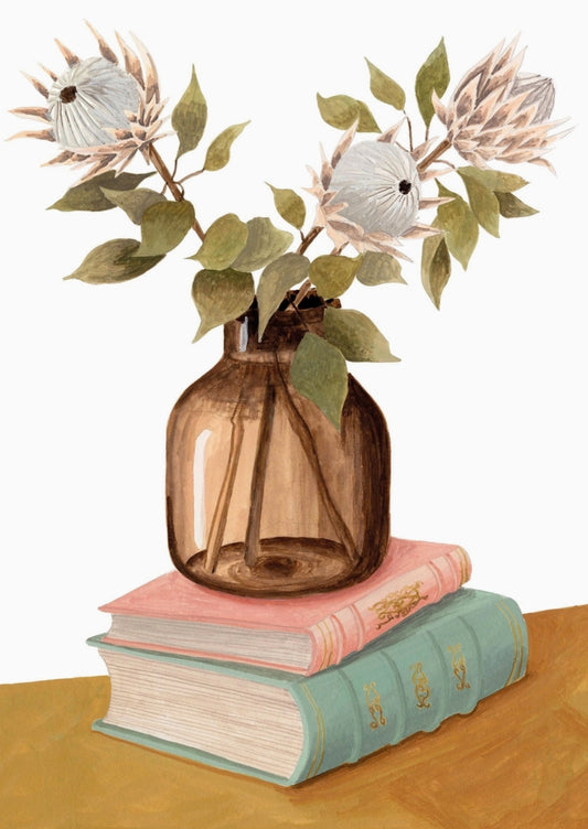Protea Postcard by Mélanie Voituriez featuring a brown glass vase filled with flowers and green leaves, placed on top of two stacked books on a wooden surface against a white background.