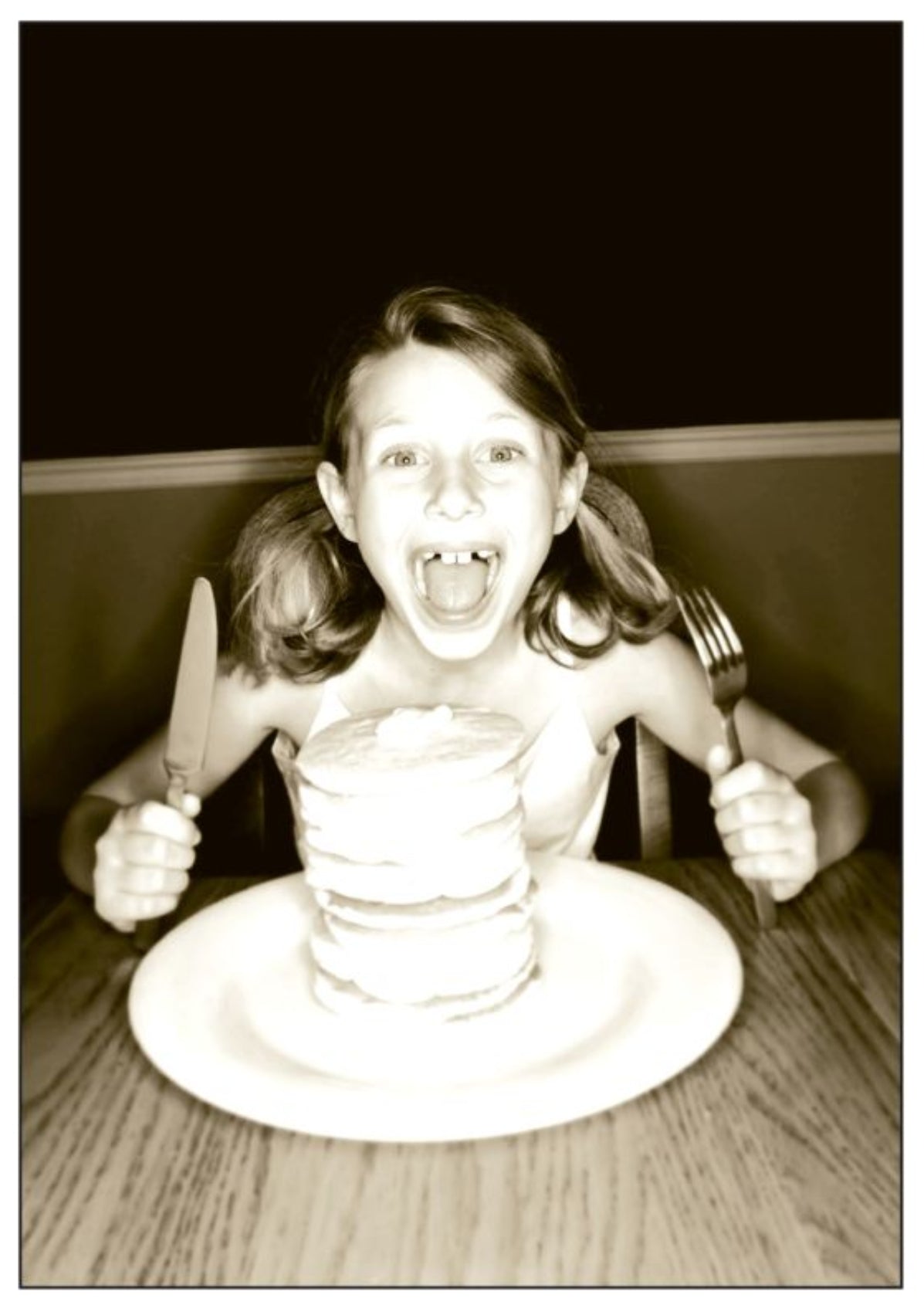 Ready to Eat - Pancakes Postcard by Gutrath Verlag featuring a sepia-toned postcard of a young girl sitting at a table, holding a knife and fork while reaching toward a large stack of pancakes on a white plate.