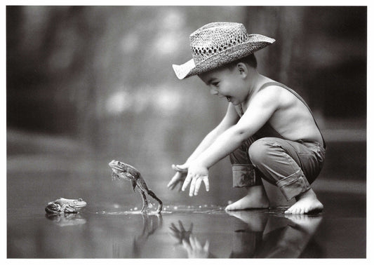 Black and white photo postcard of a child trying to catch a frog-playful vintage scene perfect for collectors, snail mail and Postcrossing.