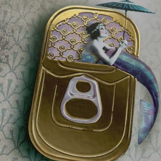 Mermaid Postcard by La Tack for Nobis Design featuring a mermaid holding an umbrella sitting in a sardine can on a decorative background. Video depicts the shiny gold foil detailing.